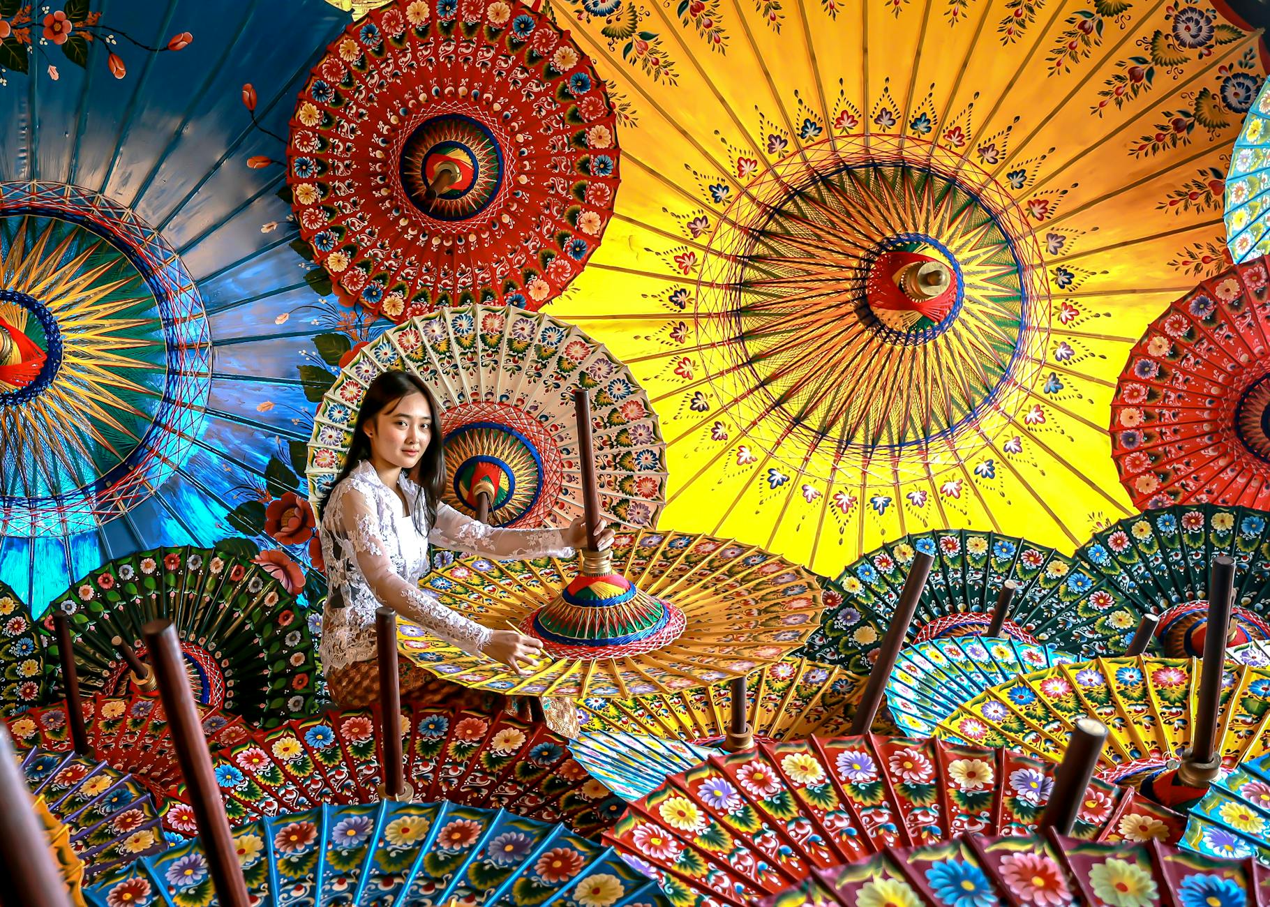 Artystka wśród kolorowych tradycyjnych parasoli na azjatyckim jarmarku