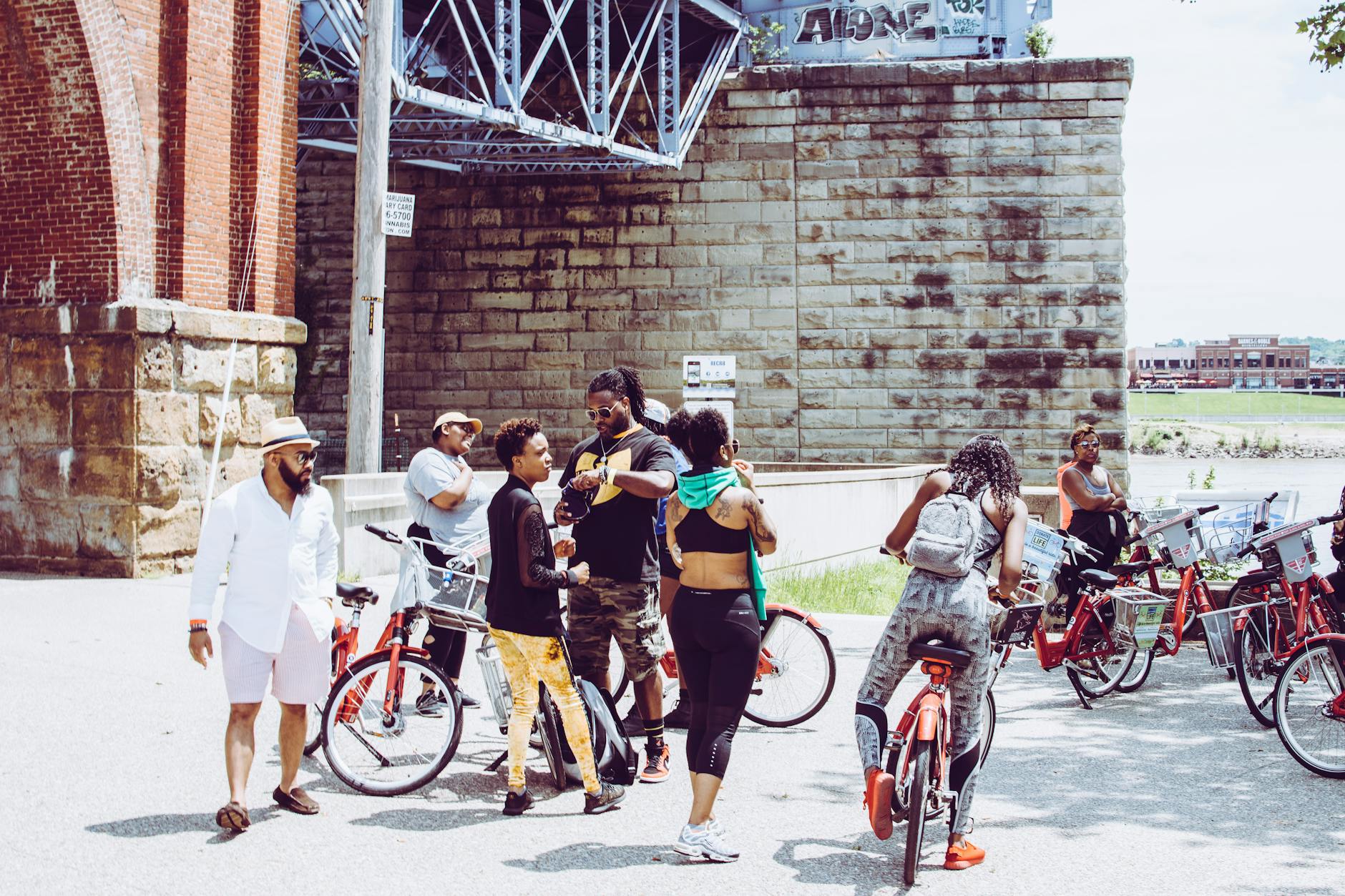 Grupa przyjaciół na rowerach odpoczywa pod mostem w słoneczny dzień