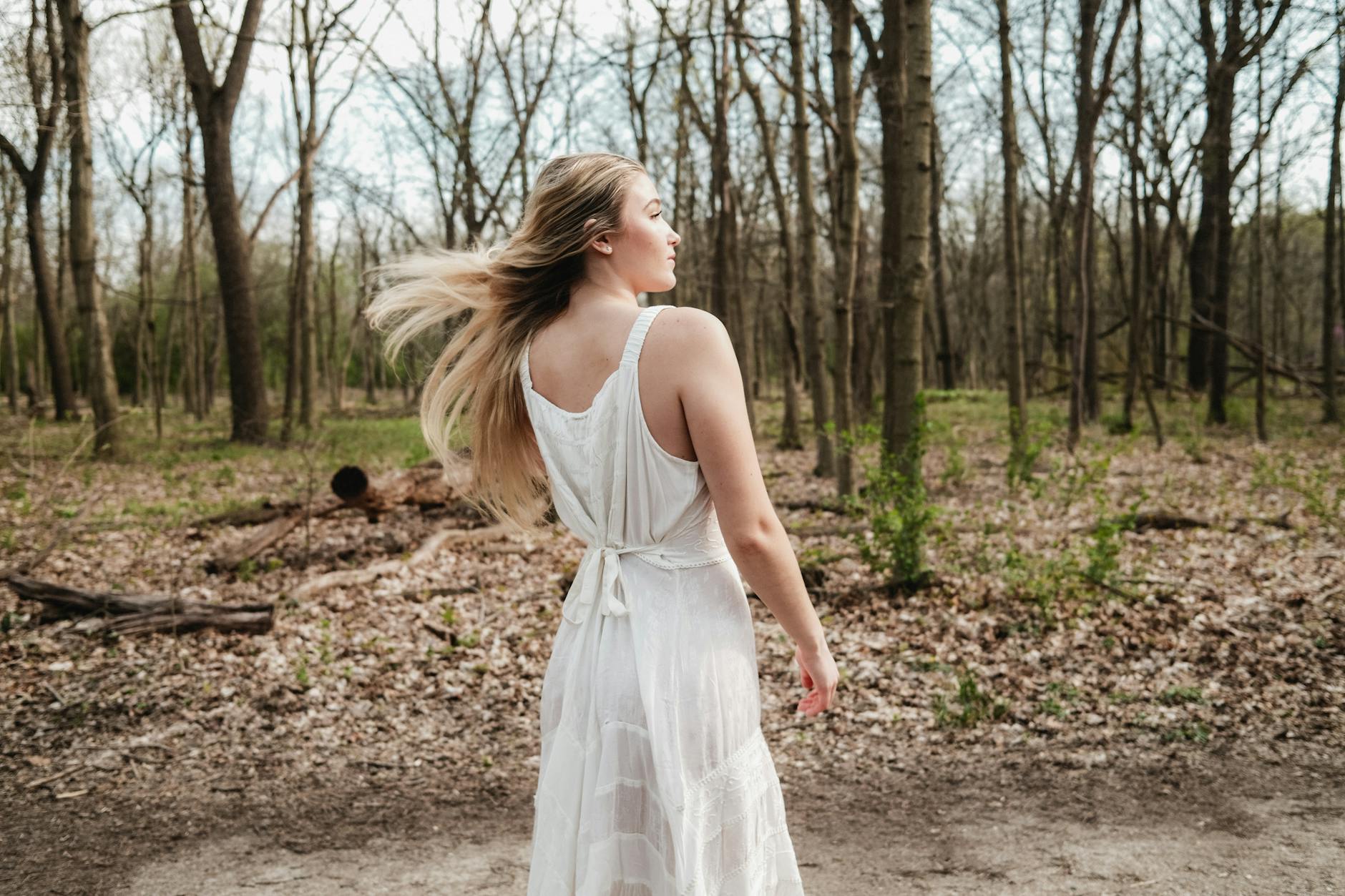 Kobieta w białej sukni idzie leśną ścieżką na szlaku z Nałęczowa