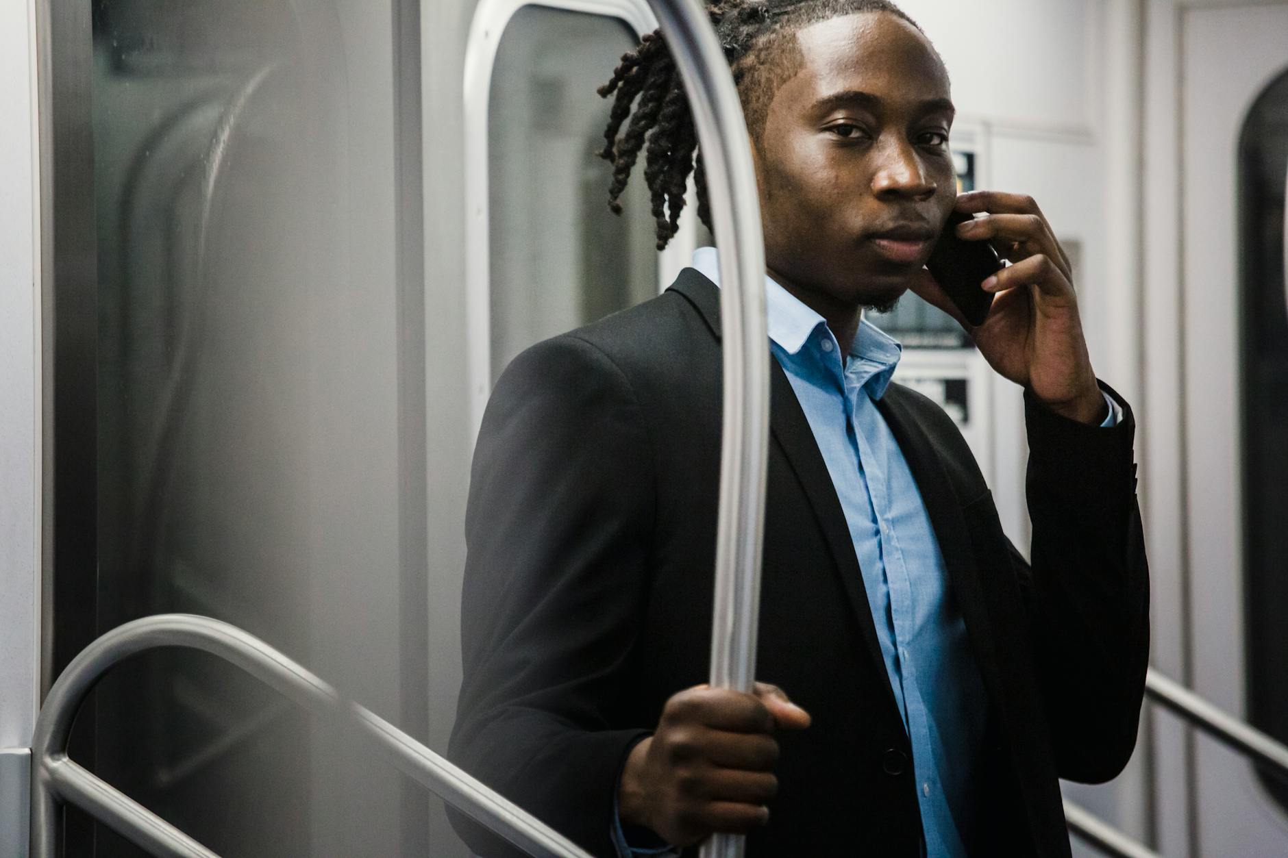 Młody mężczyzna w metrze rozmawia przez telefon w drodze z pracy