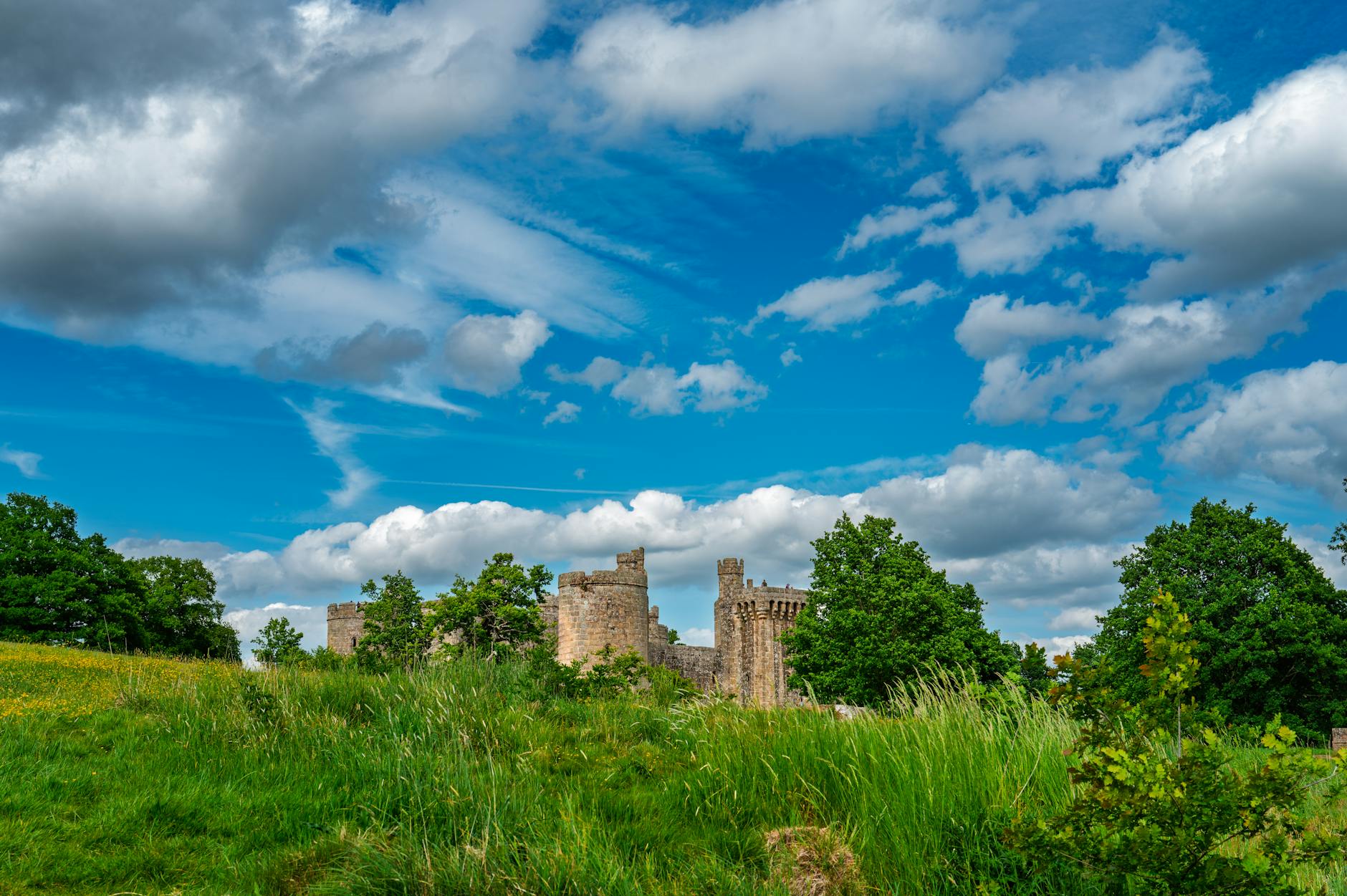 Ruiny zamku w Janowcu otoczone zielenią na tle nieba z chmurami