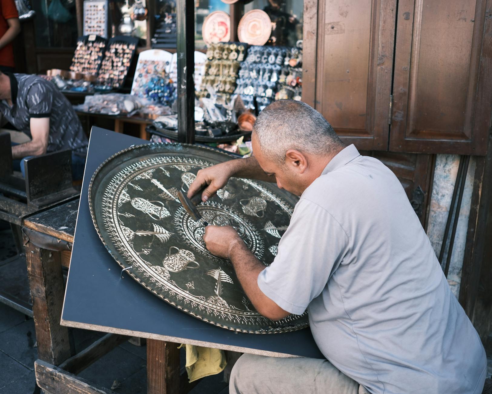 Rzemieślnik wykonuje zdobienia z metalu na straganie jarmarku