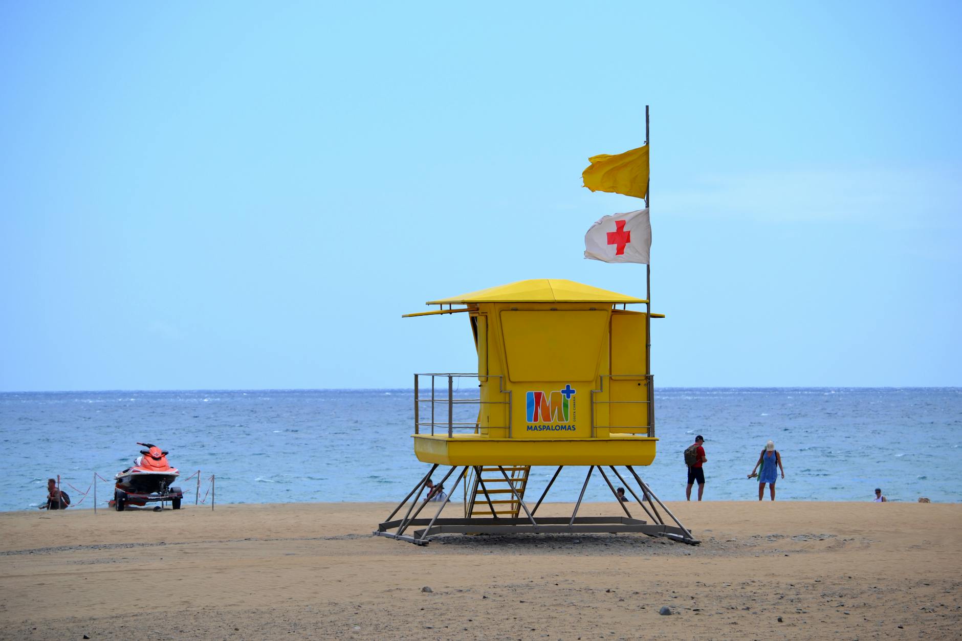Wieża ratownika z flagami na zatłoczonej plaży Maspalomas w Hiszpanii