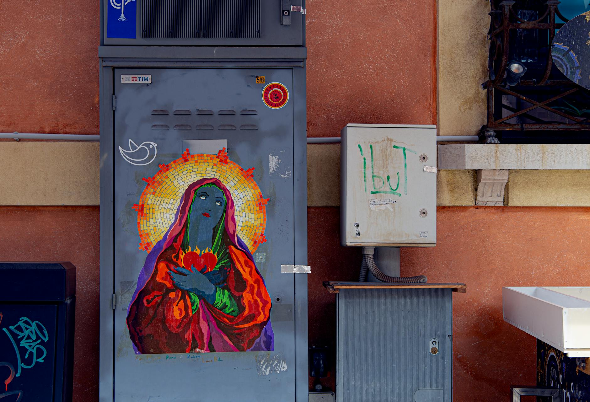 Kolorowy mural kobiety z aureolą na skrzynce na ulicy