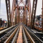 Czy Roztocze da się zwiedzić bez auta? Porady i trasy dla pociągu, busa i roweru Rdzawy most kolejowy nad torami i ulicą w miejskiej zabudowie