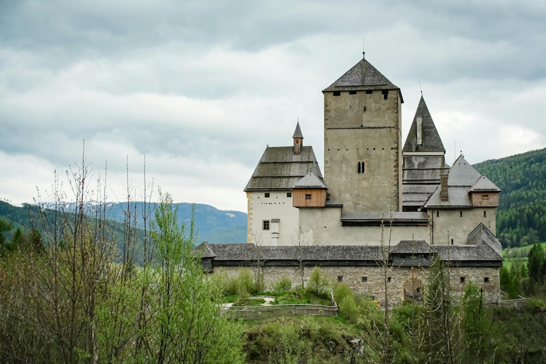 Zamek na wzgórzu otoczony zielenią w górskim krajobrazie