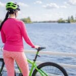 Trasa rowerowa wokół Jeziora Białego: relaks i kąpiel po drodze Kobieta na rowerze nad jeziorem w słoneczny dzień