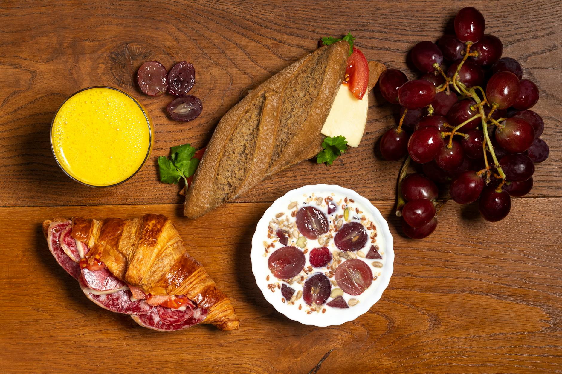 Lekkie śniadanie: croissant, bagietka, winogrona, jogurt i sok na stole