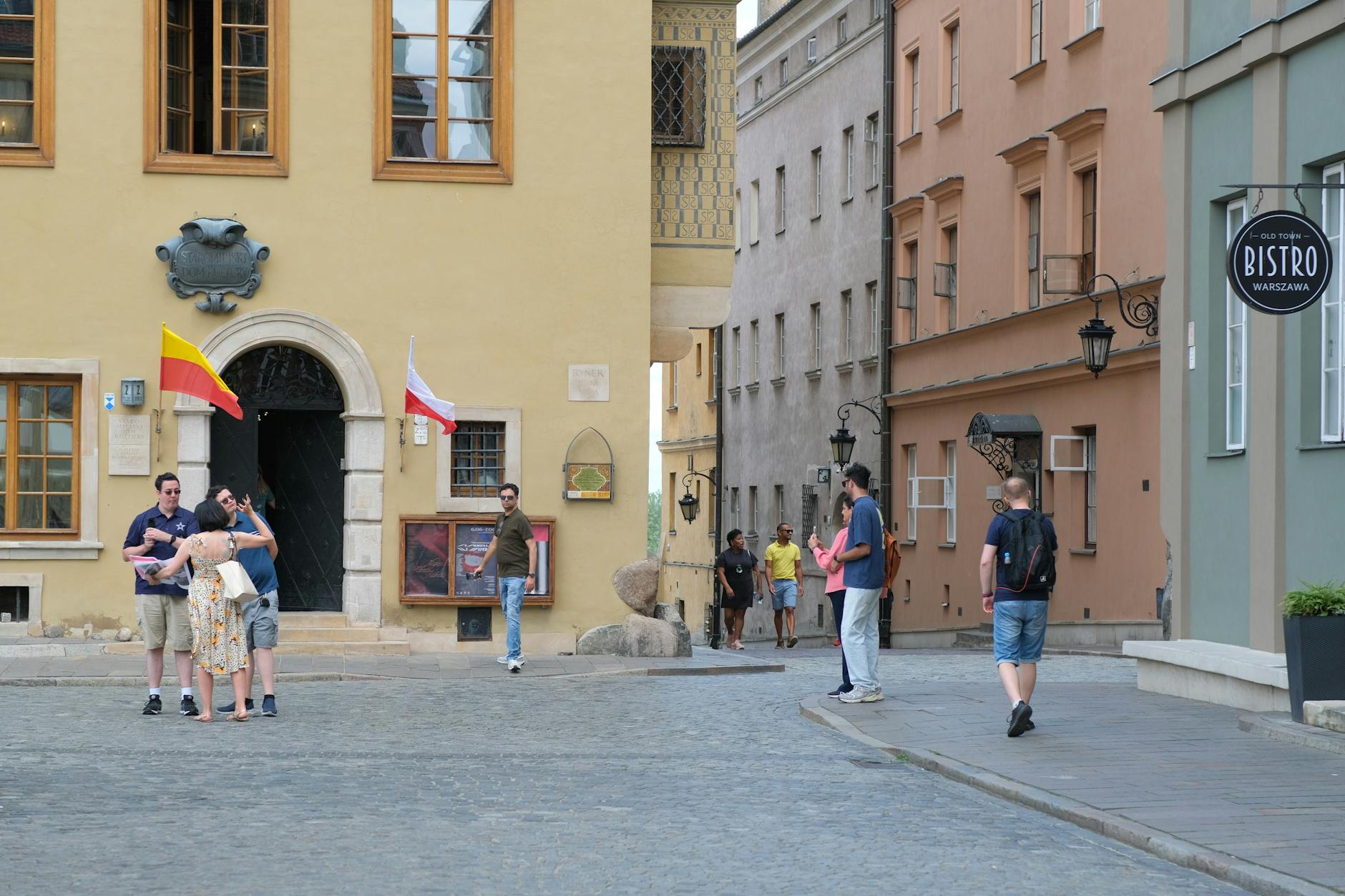 Turyści na kolorowej starówce z polskimi flagami w tle