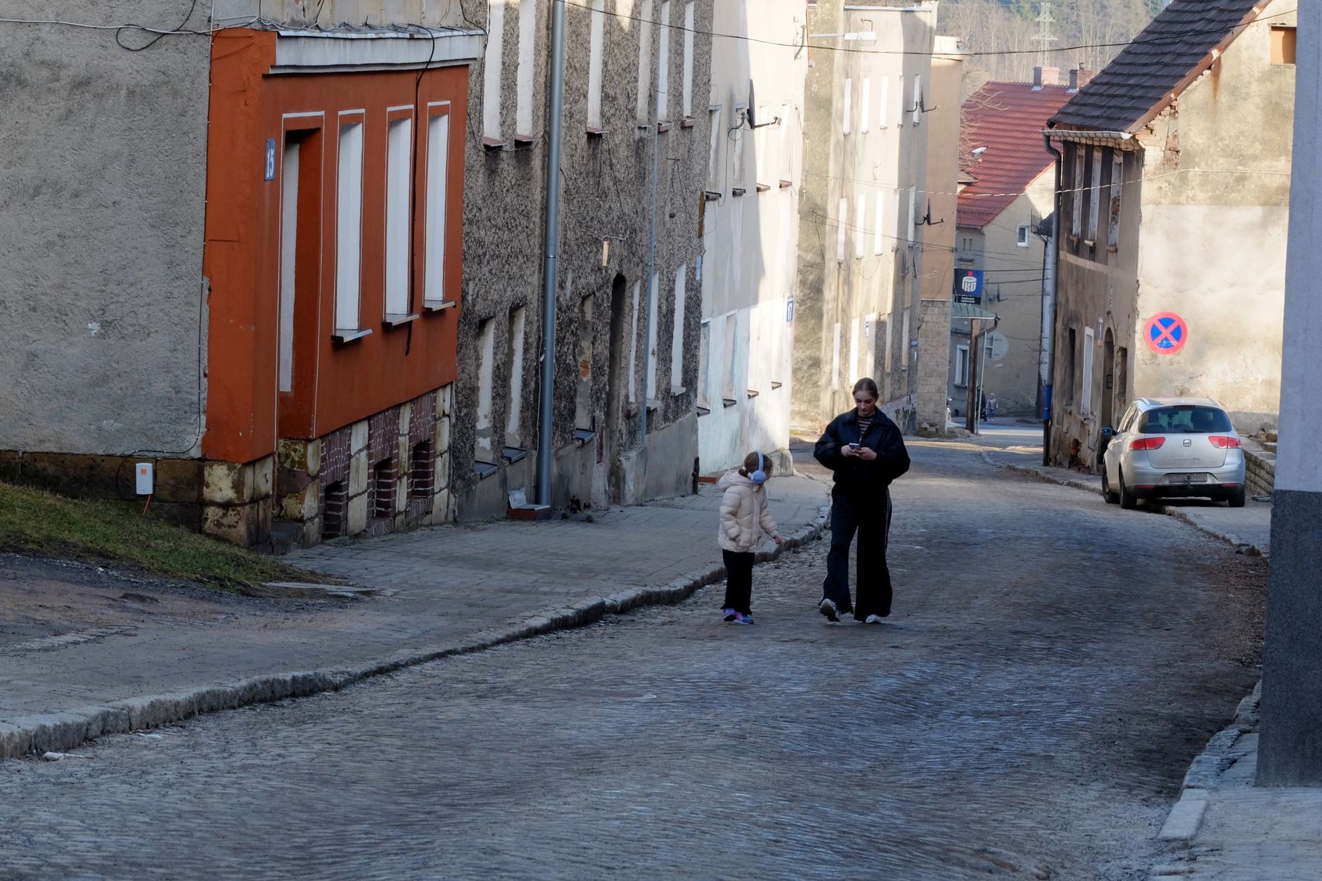 Spokojna brukowana uliczka w Kraśniku, dorosły i dziecko na wiosennym spacerze